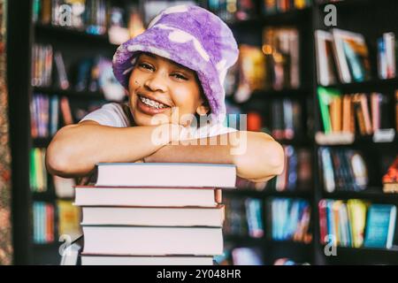 Portrait de jeune femme heureuse avec des accolades appuyées sur la pile de livres en librairie Banque D'Images