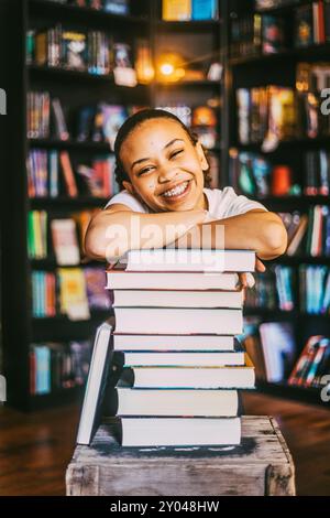 Portrait d'une jeune femme heureuse appuyée sur une pile de livres en librairie Banque D'Images