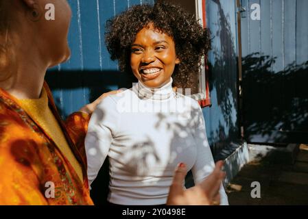 Heureuse jeune femme en col roulé parlant avec une amie au dîner Banque D'Images