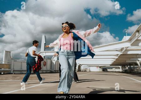 Jeune femme à la mode insouciante dansant dans un parking sous le ciel nuageux Banque D'Images