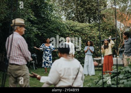 Joyeux membres de la famille masculins et féminins s'amusant pendant la réunion sociale à la fête du jardin Banque D'Images