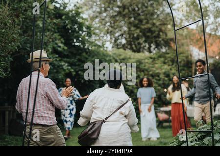 Joyeux membres de la famille masculins et féminins accueillant les grands-parents lors de la réunion sociale à la fête du jardin Banque D'Images