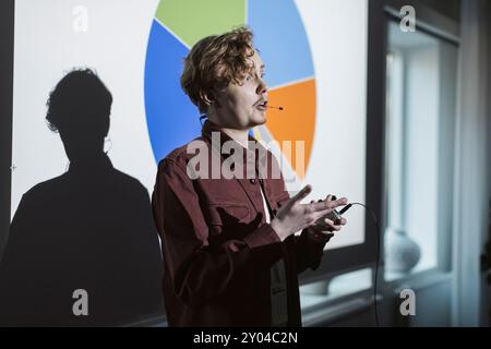 Jeune entrepreneur masculin donnant la parole près de l'écran de projection pendant le séminaire Banque D'Images