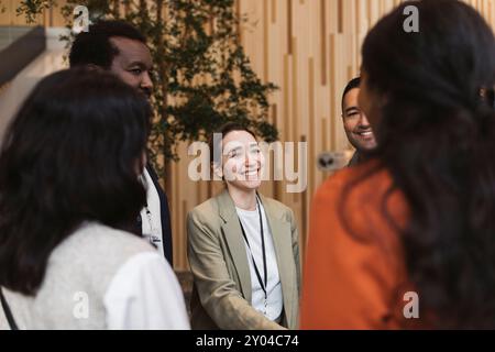Femme entrepreneure souriante interagissant avec les délégués dans le séminaire au centre de congrès Banque D'Images