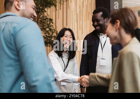 Heureuse entrepreneure faisant poignée de main avec le jeune délégué pendant le séminaire au centre des congrès Banque D'Images