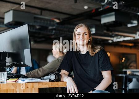 Portrait d'une jeune programmeuse de technologie souriante assise au bureau dans le bureau Banque D'Images