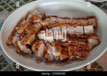 Un gros plan d'un succulent ventre de porc croustillant, tranché et disposé sur une assiette blanche. Banque D'Images