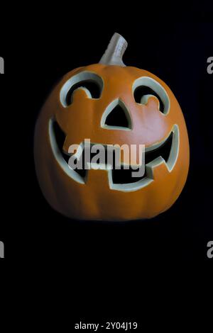 Un gros plan d'une citrouille sculptée Jack-o-lanterne avec un visage souriant, isolé sur un fond noir. Banque D'Images