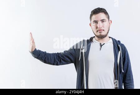 Jeune homme faisant un geste de rejet avec la paume de la main isolé. La personne mécontente qui rejette les gestes arrête isolé Banque D'Images