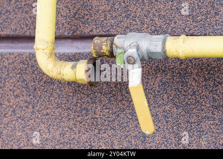 Un tube à gaz jaune, avec robinet, à l'extérieur d'une maison pour canaliser l'énergie douce à la maison Banque D'Images