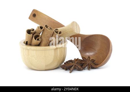 Mortier en bois rempli de bâtonnets de cannelle, anis étoilé dans une cuillère en bois isolée sur fond blanc Banque D'Images