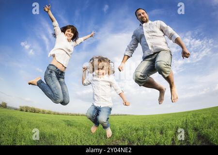 Happy active family jumping in green field. Concept de vacances d'été Banque D'Images