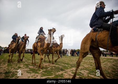 Gaza, Palestine. 18 mars 2023. Les Palestiniens montent à dos de chameaux parmi les drapeaux nationaux palestiniens lors d'une course dans la ville de Gaza de Deir El-Balah pour commémorer la Journée de la Terre. La Journée de la terre tombe le 30 mars et commémore et rend hommage aux six Palestiniens tués et aux centaines de blessés par la police israélienne, alors qu’ils protestaient contre l’expropriation par le gouvernement israélien de terres palestiniennes en Galilée, dans le Naqab et à Wadi Ara en 1976 Banque D'Images