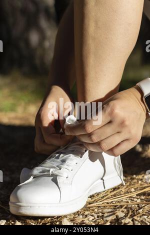 Détail vertical de jeune fille sportive souriant et attachant ses lacets pour aller courir. Lifestyle Sport concept Banque D'Images