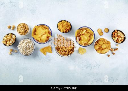 Collations salées, mélange de fête. Un assortiment de hors-d'œuvre croustillants, pris d'en haut sur un fond d'ardoise avec espace de copie. Chips de pommes de terre et tortilla, craquelin Banque D'Images