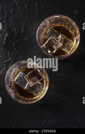 Whisky dans des verres avec glace. Whisky Bourbon sur des rochers sur fond d'ardoise noire, tiré d'en haut Banque D'Images