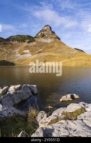 Lac Augstsee et la montagne Atterkogel sur le perdant. Roches au premier plan. Automne, beau temps, ciel bleu. Altaussee, Bad Aussee, Ausseer Land, Banque D'Images
