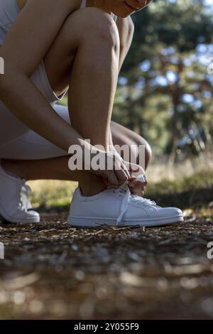 Détail de jeune fille sportive attachant ses lacets pour aller courir dans la campagne.concept de sport et de vie saine Banque D'Images