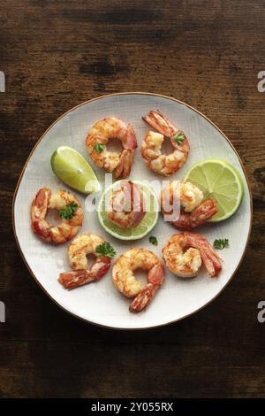 Crevettes, top shot. Crevettes cuites au citron vert sur une assiette blanche sur une table en bois rustique. Cuisine espagnole Banque D'Images