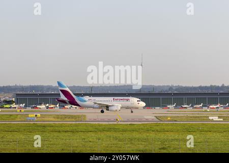 Eurowings atterrissant sur une piste devant un hangar sous un ciel ensoleillé, avec la tour de télévision de Stuttgart en arrière-plan, Baden-Wuerttembe Banque D'Images