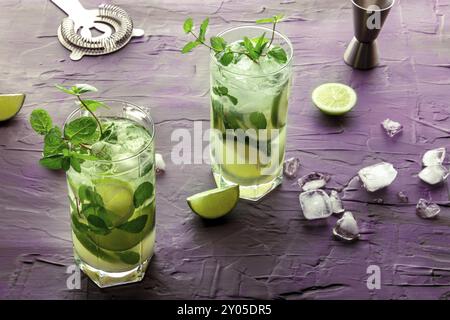 Cocktail Mojito, deux verres. Boisson froide d'été avec citron vert, menthe fraîche et glace. Boisson fraîche sur un fond violet Banque D'Images