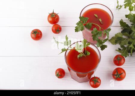 Tomates mûres et jus de persil sur fond de bois blanc Banque D'Images