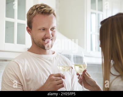 Happy young couple bénéficiant d''un verre de vin blanc à la cuisine Banque D'Images