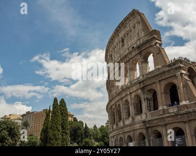 Impressionnant Colisée avec arcades et ciel nuageux, arbres et bâtiments en arrière-plan, Rome, Italie, Europe Banque D'Images