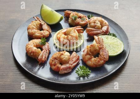 Crevettes avec des limes et du persil. Crevettes grillées sur une table rustique. Hors-d'œuvre de fruits de mer épicés Banque D'Images