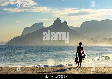 Jeune bodyboarder regardant la mer et la plage d'Ipanema au cours d'un après-midi ensoleillé Banque D'Images