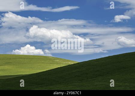 Le passage de nuages blancs au-dessus de la verdure des collines de la Val d'Orcia dans une ambiance chaleureuse et ensoleillée journée de printemps Banque D'Images