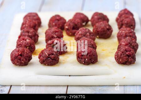 Boulettes de viande crues sur une planche à découper Banque D'Images