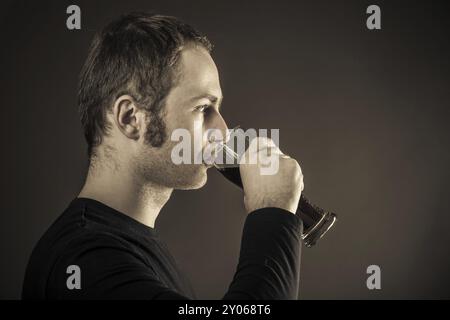 Homme buvant de la bière sur fond sombre. Gros plan Banque D'Images