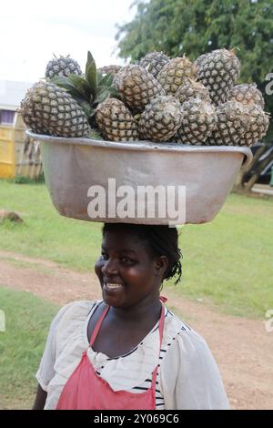 Jeune femme portant un grand bol d'ananas sur sa tête Banque D'Images