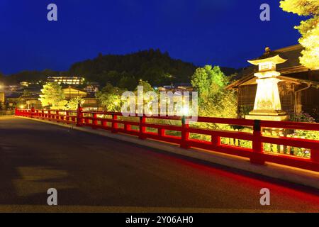 Lampe en pierre illuminée et clôture de pont Naka-Bashi rouge vif, pont en asphalte, entrant dans la vieille ville de Takayama dans la préfecture de Gifu, Japon sous un bleu foncé Banque D'Images