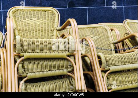 Chaises empilées en osier sur un mur de maison Banque D'Images