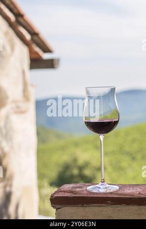 Dégustez un verre de vin rouge à Tuscany, Italie. Jardins à vin flous en arrière-plan Banque D'Images