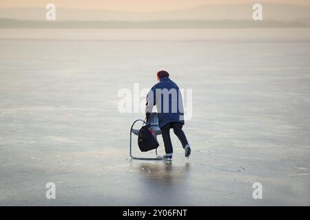 Femme âgée avec une chaise avec des coureurs sur la glace, Steinhuder Meer, basse-Saxe Banque D'Images