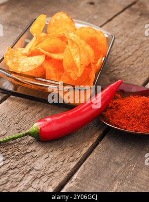 Croustilles de pommes de terre épicées avec un pepperoni rouge sur une table de cuisine en bois rustique Banque D'Images