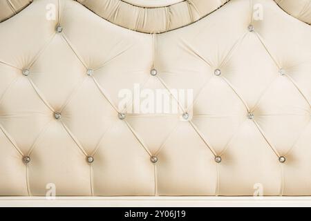 Fond textile doux beige avec boutons symétriques sur les coins des diamants. Eléments de mobilier doux et coûteux. Fond de luxe Banque D'Images