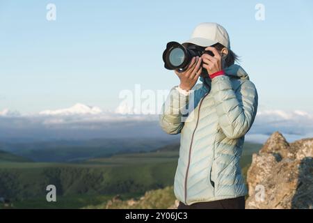 Portrait d'une jeune photographe dans un chapeau sur la nature en photographiant sur son appareil photo numérique miroir. Vue avant Banque D'Images