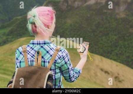 Une jeune fille hipster a voyagé avec un blogueur dans une chemise à carreaux et avec des cheveux multicolores en utilisant une boussole en arrière-plan dans le fond du Caucasi Banque D'Images