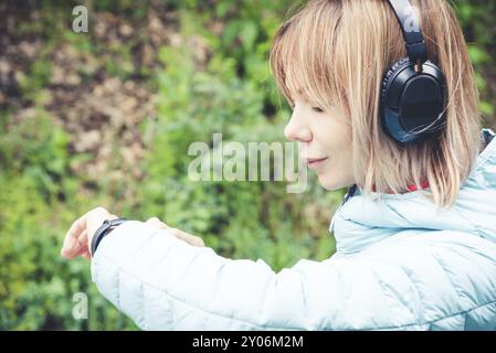 Portrait jeune femme de fitness regardant sa montre intelligente tout en prenant une pause de l'entraînement sportif. Sportive vérifiant le pouls sur la montre intelligente de fitness d Banque D'Images