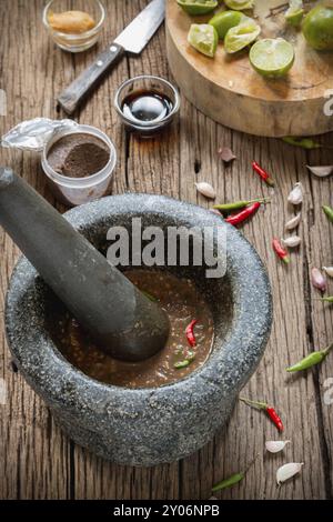 Pâte de crevettes sauce piment dans une pierre de mortier avec des ingrédients à cuire Banque D'Images