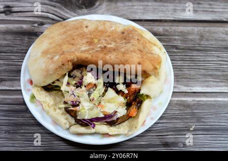 Un pain pita syrien Shami rempli d'aubergines égyptiennes traditionnelles frites à l'ail, entouré de tomates fraîches et croquantes en dés, de concombre Banque D'Images