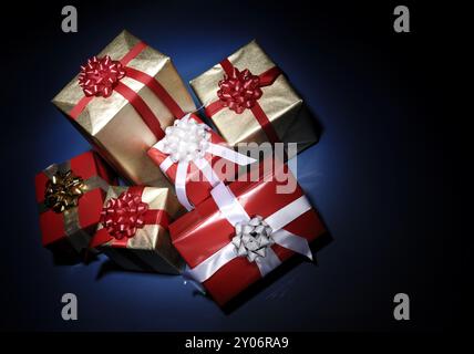 Pile de cadeaux de Noël allumé dans les ténèbres isolé sur fond bleu foncé Banque D'Images