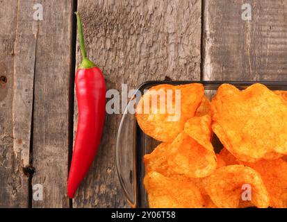 Croustilles de pommes de terre épicées avec un pepperoni rouge sur une table de cuisine en bois rustique Banque D'Images