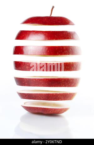 Tranches de pomme rouge suspendues dans l'air isolé sur fond blanc. Concept de génie génétique alimentaire Banque D'Images