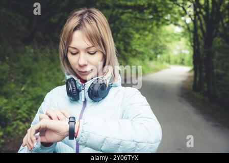 Portrait jeune femme de fitness regardant sa montre intelligente tout en prenant une pause de l'entraînement sportif. Sportive vérifiant le pouls sur la montre intelligente de fitness d Banque D'Images