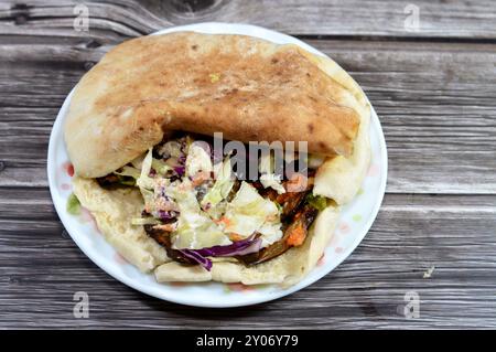 Un pain pita syrien Shami rempli d'aubergines égyptiennes traditionnelles frites à l'ail, entouré de tomates fraîches et croquantes en dés, de concombre Banque D'Images